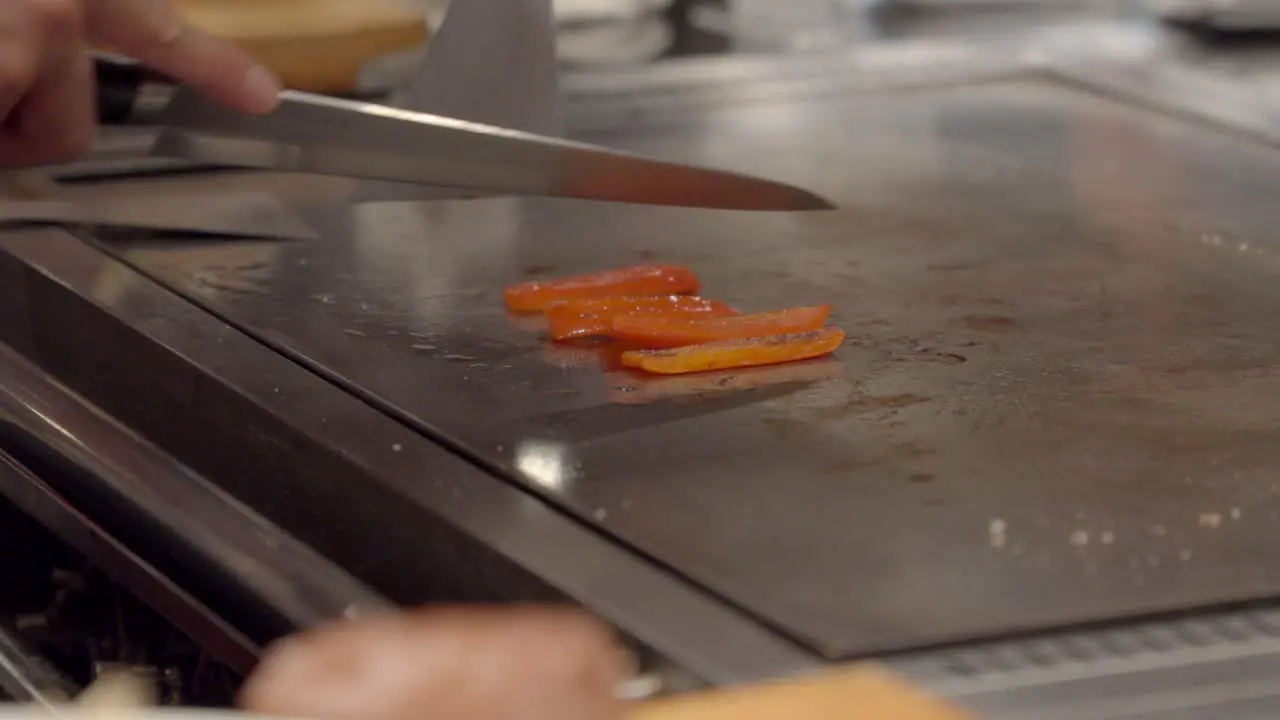 Teppanyaki chef cooker slice vegetable red pepper over hot table at Osaka Kobe Japan authentic experience