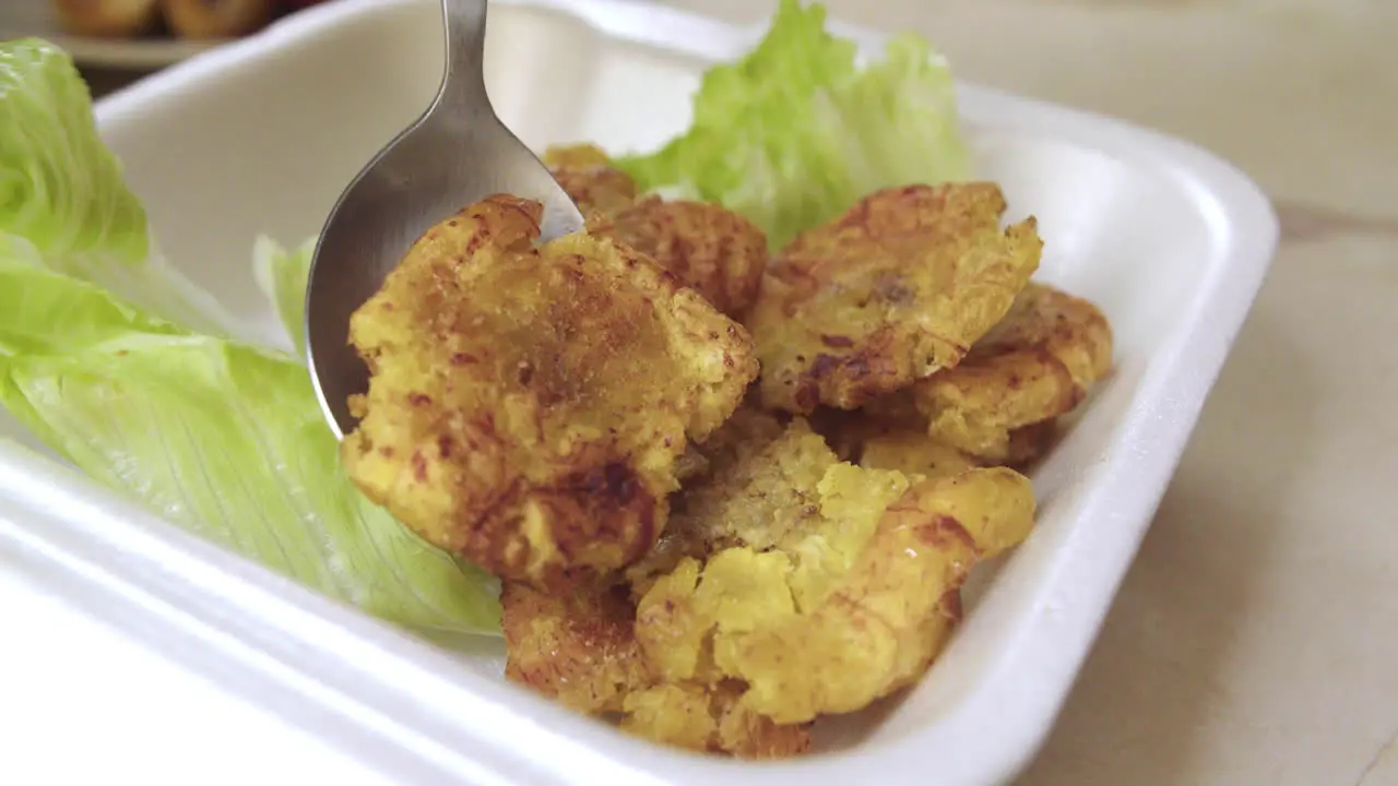 Primer plano de plato peruano de la selva con patacones o tostones siendo colocados en un recipiente