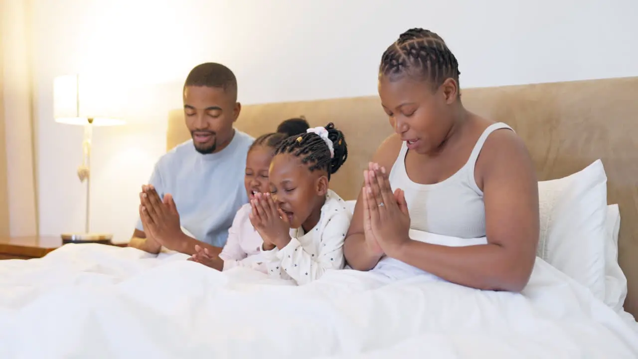 Black family parents and children praying in bed