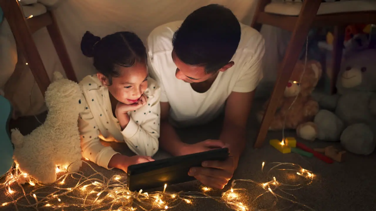 Tent father and girl on tablet at night watching