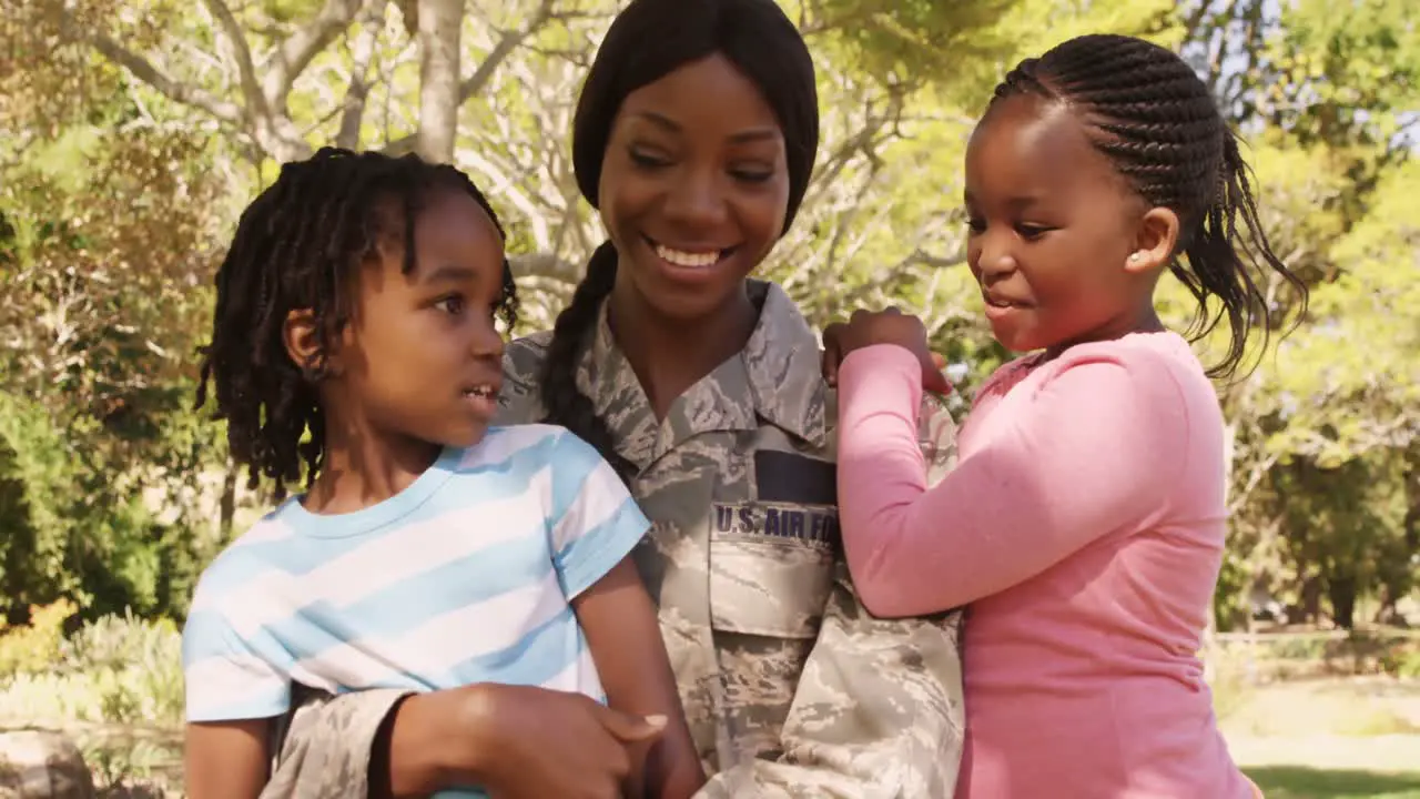 Soldier mother holding her two children in a park