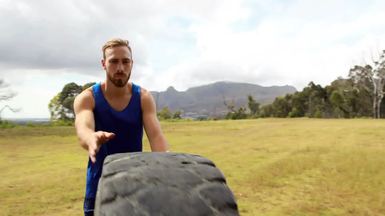 Fit man pushing heavy tyre during obstacle course