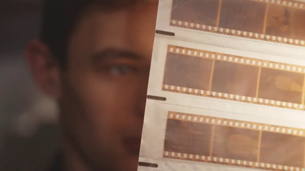 Man Looking At Old Vintage Film Negative Strips