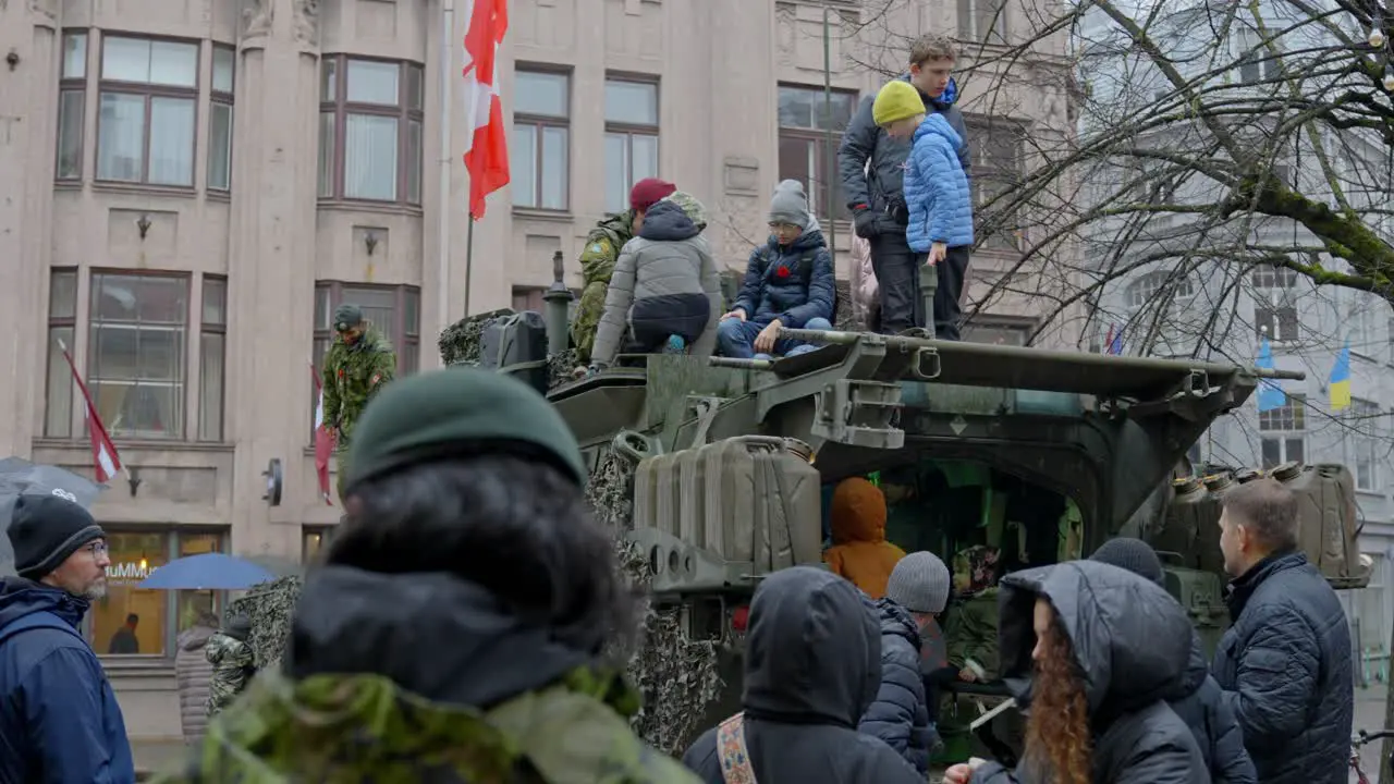 Military parade civils looking at LAV 6 vehicle with soldiers around Riga