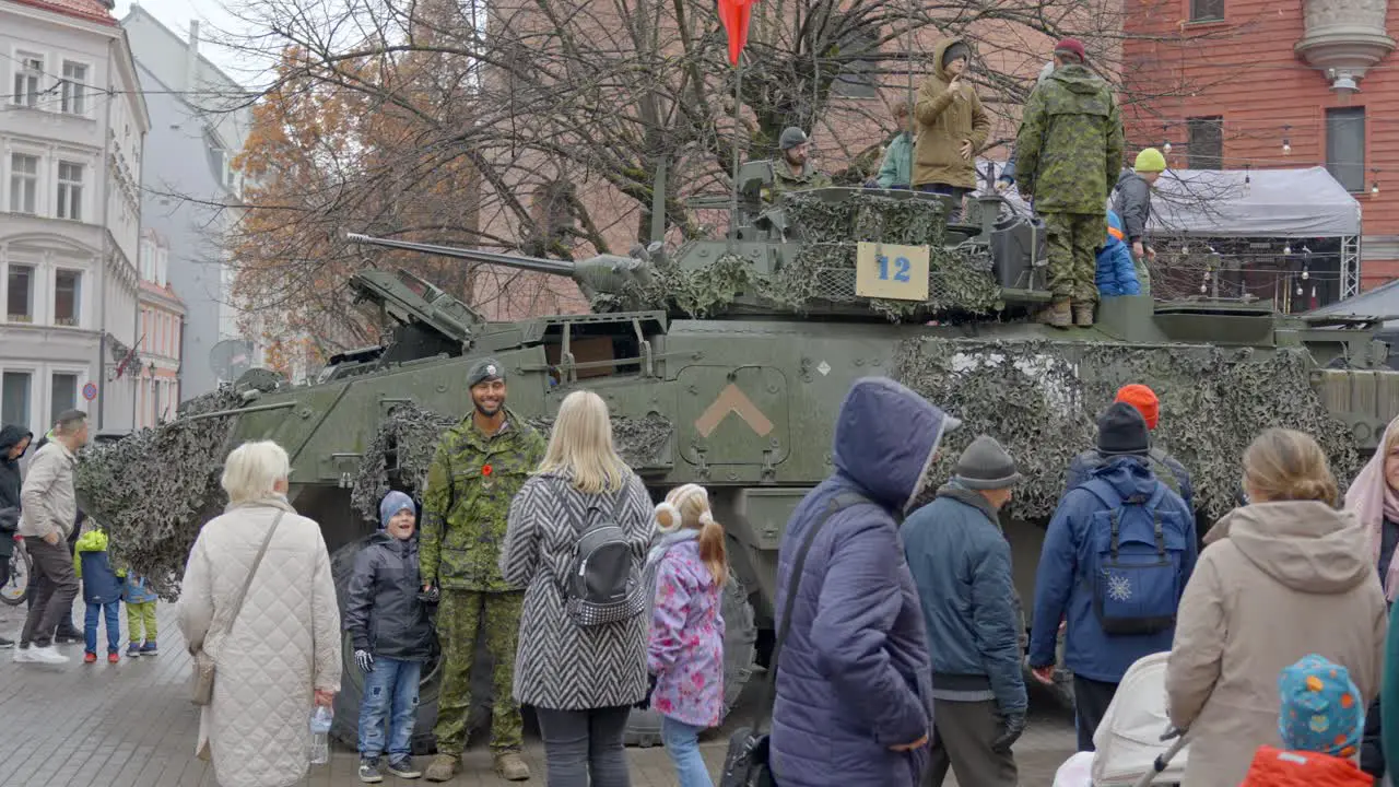 Military parade parked LAV 6 vehicle with people taking pictures with soldiers