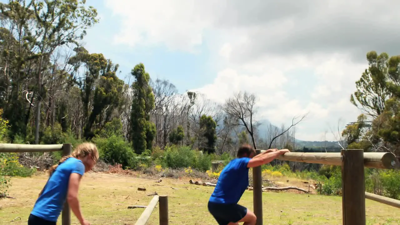 Fit man and woman climb a hurdles during obstacle course