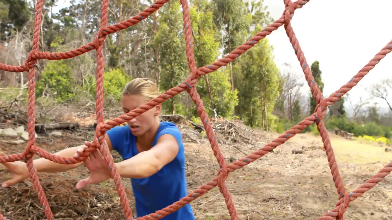 Fit woman climbing a net during obstacle course