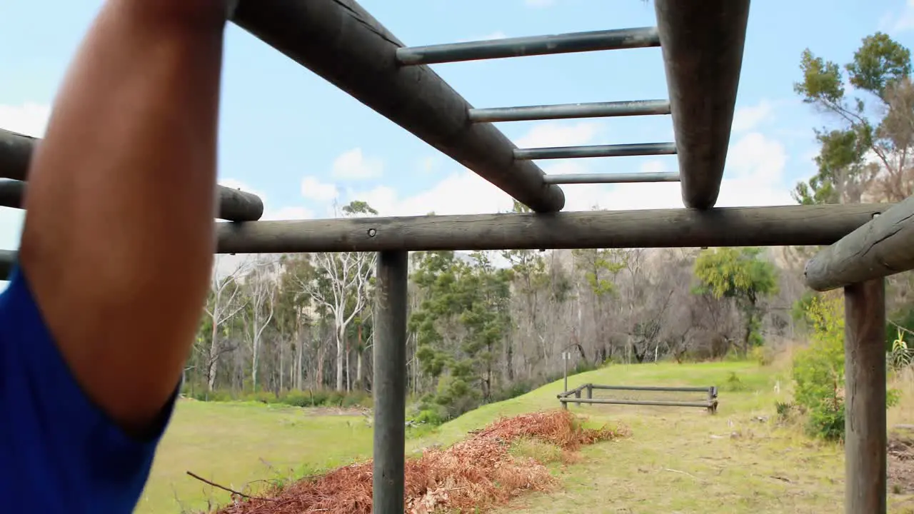 Fit man and woman climbing monkey bars during obstacle course