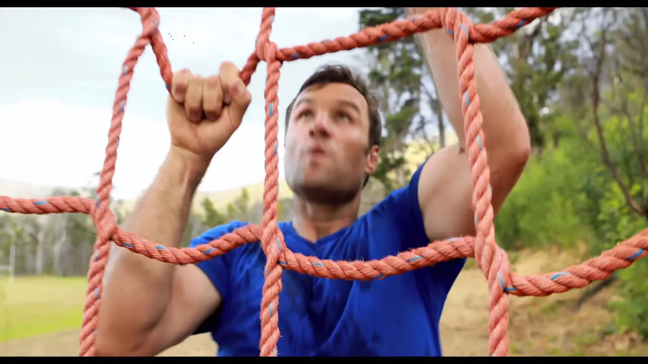 Fit man climbing a net during obstacle course