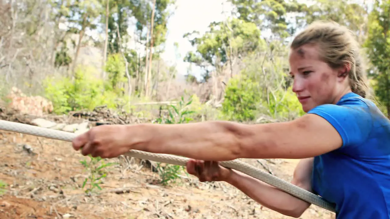 Fit woman playing tug of war during obstacle course