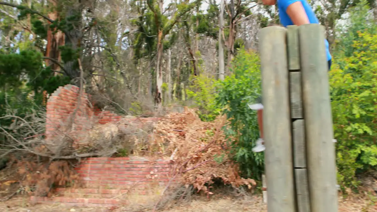 Fit man and woman to climb a wooden wall during obstacle course