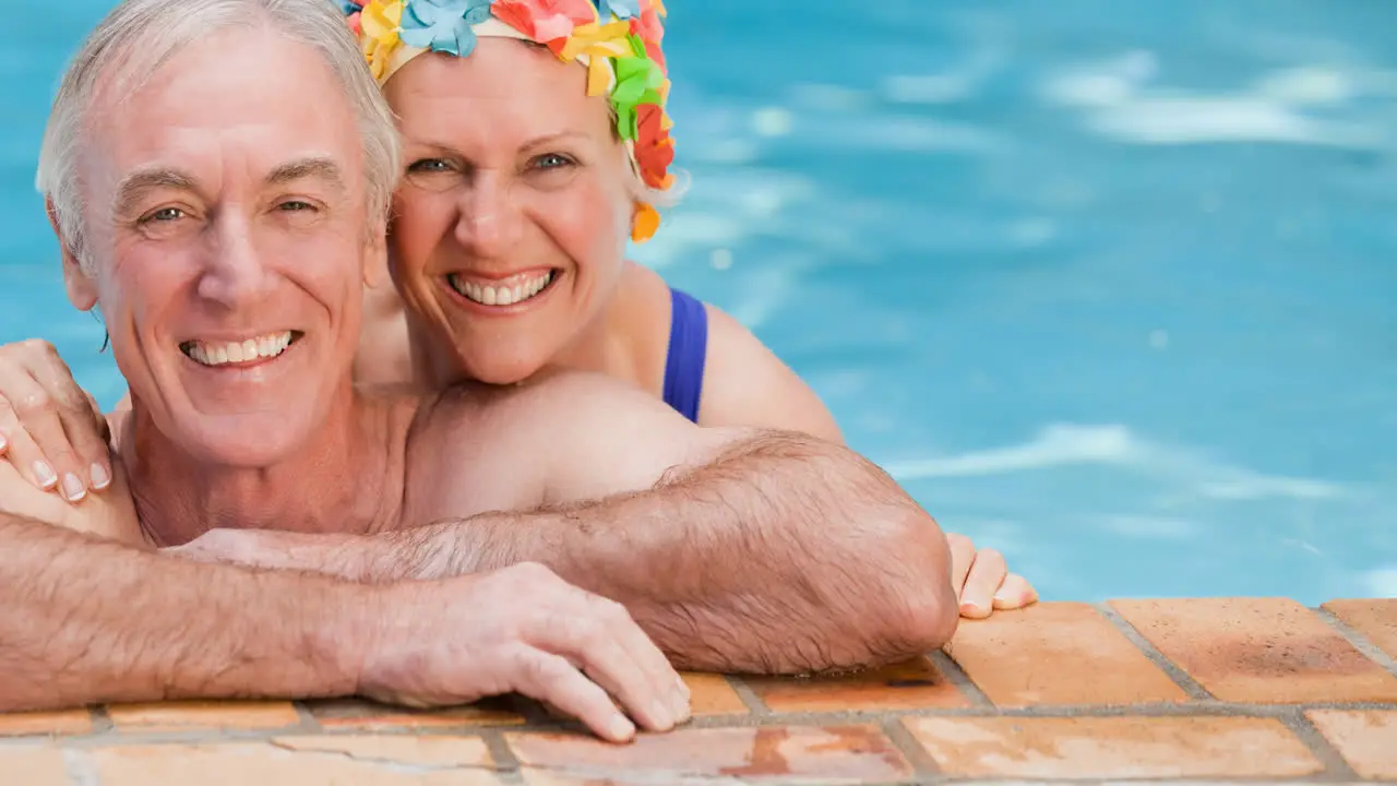 Portrait of smiling caucasian senior couple on holiday in swimming pool