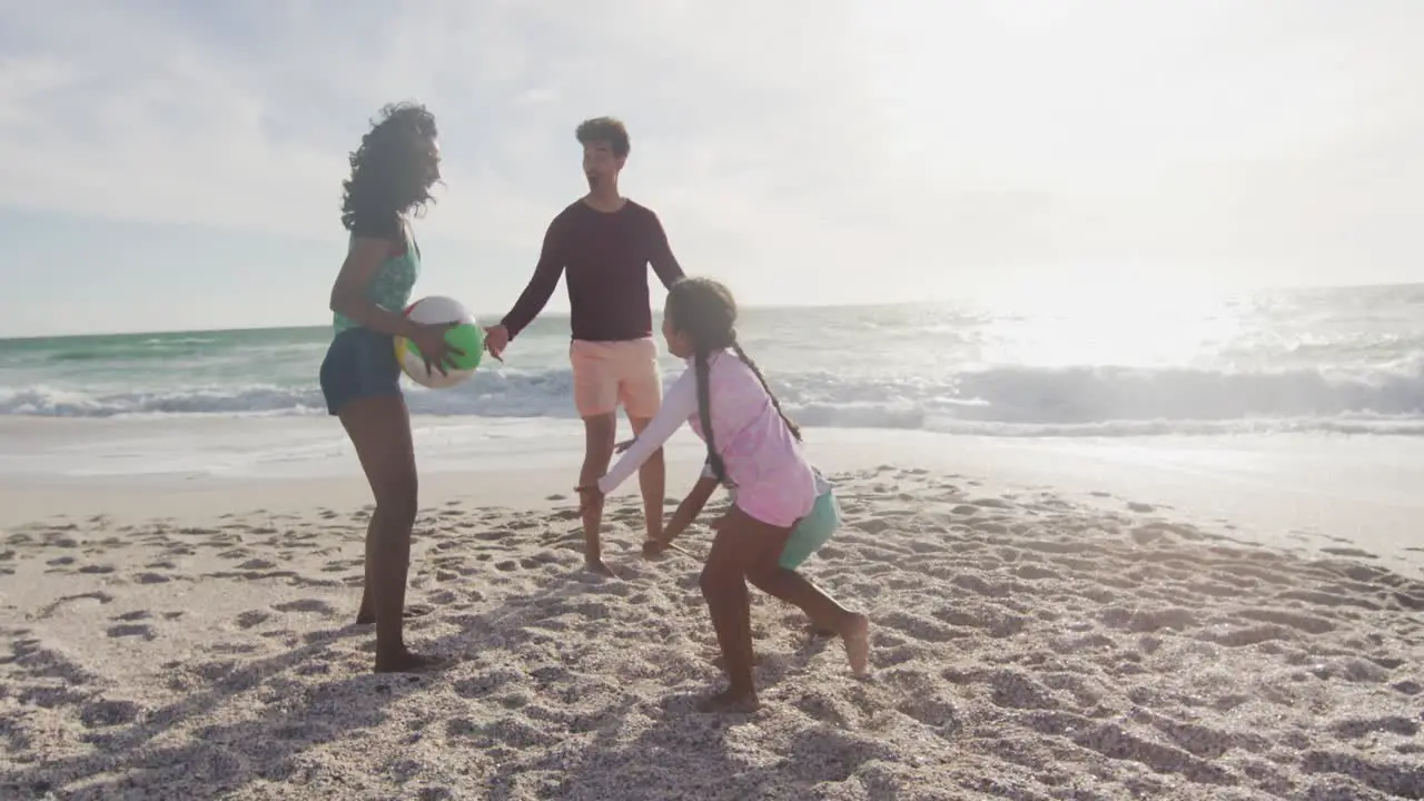 Happy hispanic mother father son and daughter playing with ball on beach