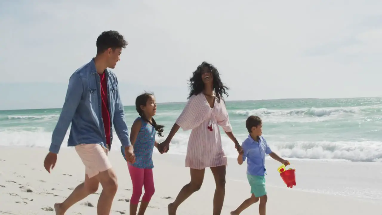 Happy hispanic mother father son and daughter walking on beach