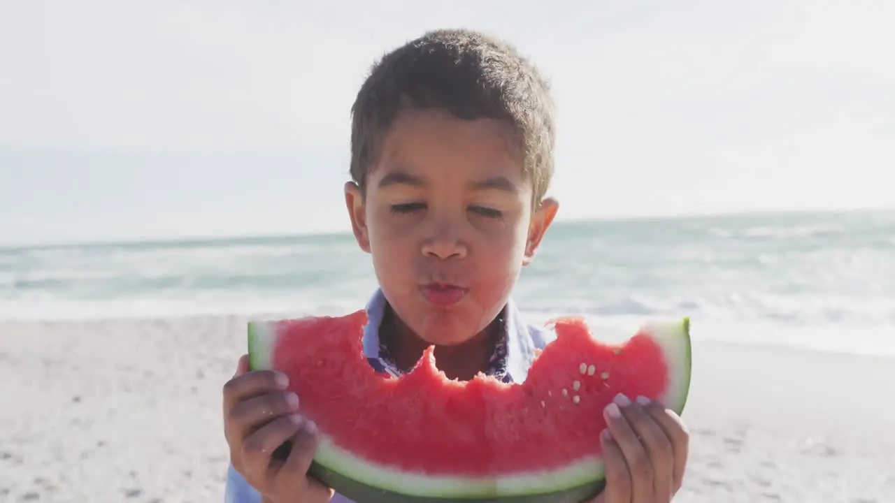 Portrait of happy hispanic boy eating watermelon on beach