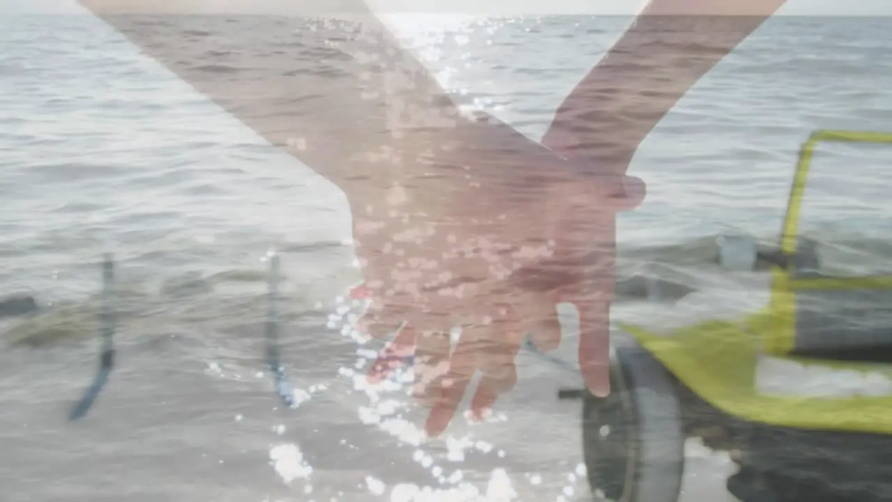 Animation of light over hands of caucasian couple walking on beach