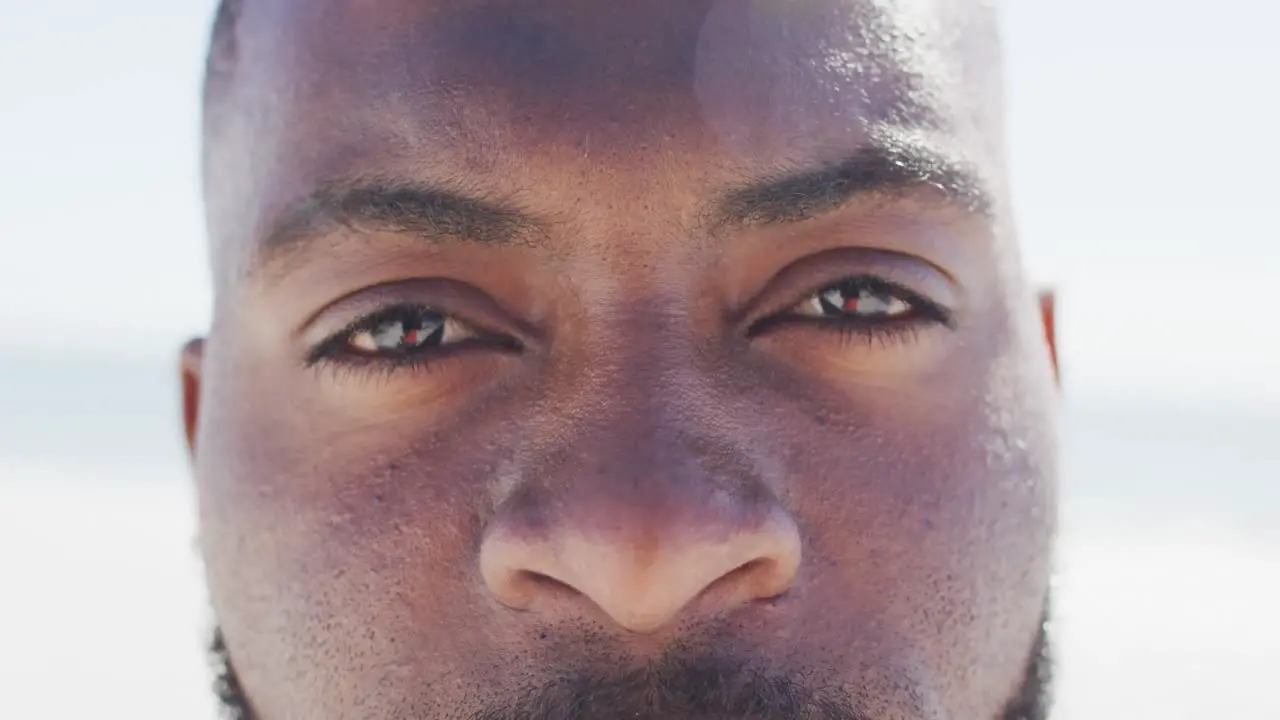 Video of face of african american man looking at camera on beach