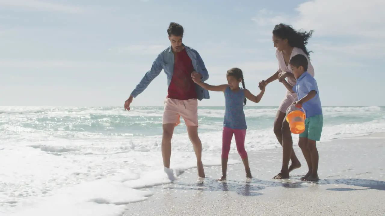 Happy hispanic mother father son and daughter playing in sea at the beach