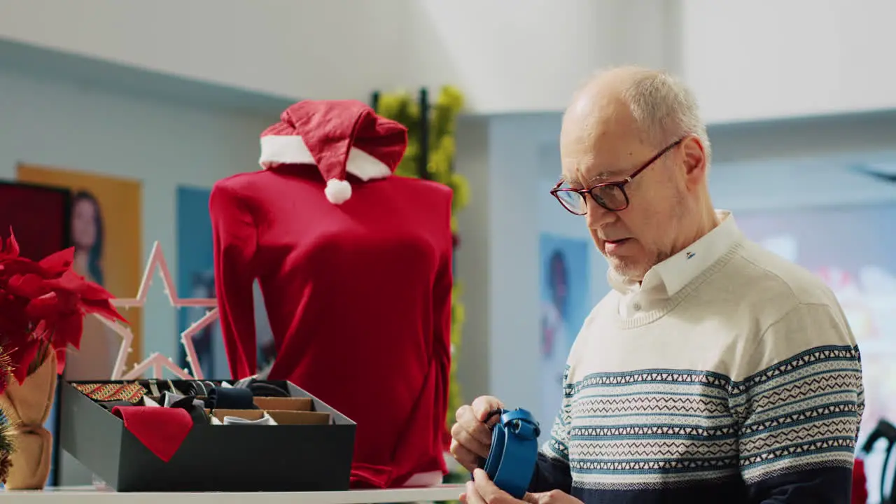 Elderly man browsing exquisite fashionable belt collection in Christmas decorated store during winter holiday season Senior customer interested in festive gifts for nephews