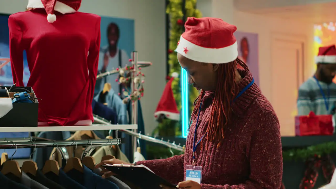 Portrait of cheerful manager browsing through festive clothing display in Christmas shopping store making sure clothes are ready for customers during winter holiday bargains season