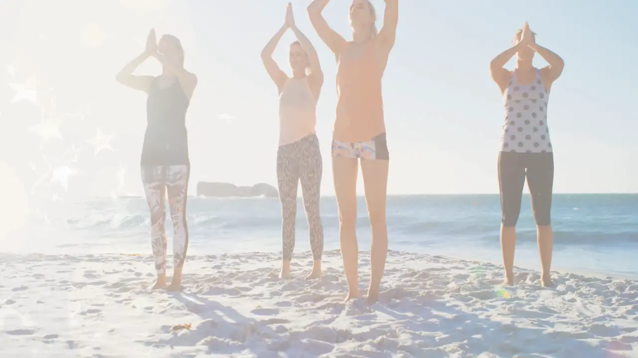 Animation of glowing lights over group of diverse female friends exercising yoga by the sea