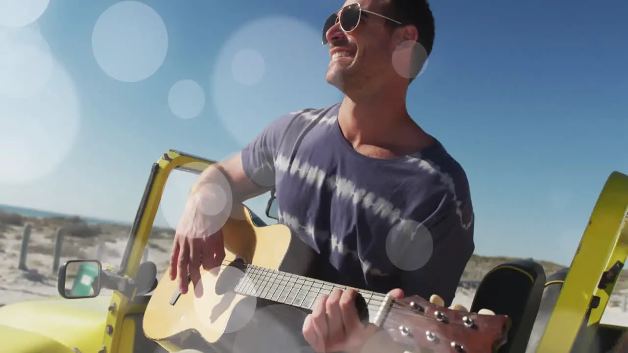 Animation of dots over happy caucasian man with guitar on beach