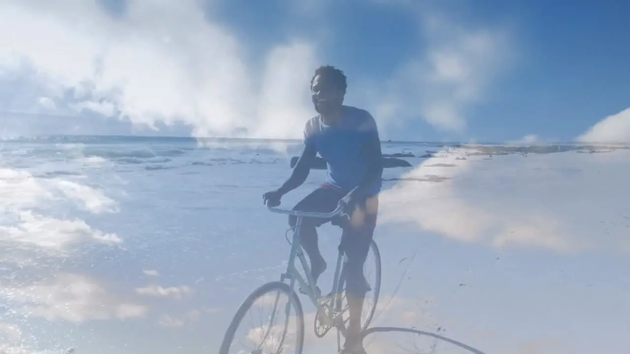 Animation of clouds over happy african american man with bike on beach