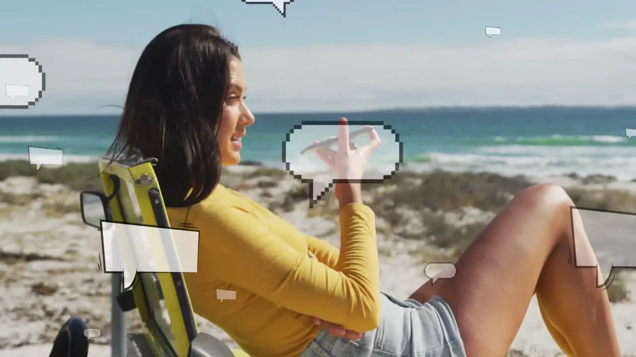 Animation of social media reactions over happy caucasian woman with smartphone on beach