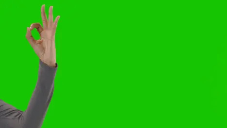 Studio Close Up Shot Of Woman Giving OK Sign Against Green Screen