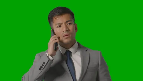 Studio Shot Of Serious Businessman In Suit Taking Call On Mobile Phone Against Green Screen 1