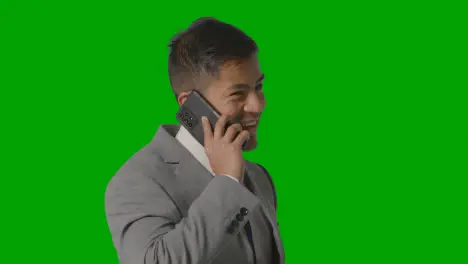 Studio Shot Of Smiling Businessman In Suit Talking On Mobile Phone Against Green Screen 1