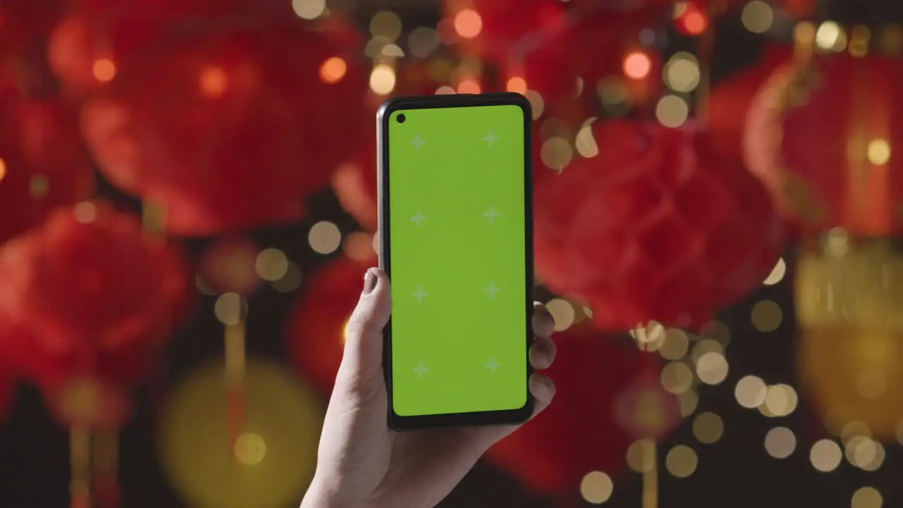 Hand Holding Green Screen Mobile Phone With Chinese Lanterns Hung In Background 1