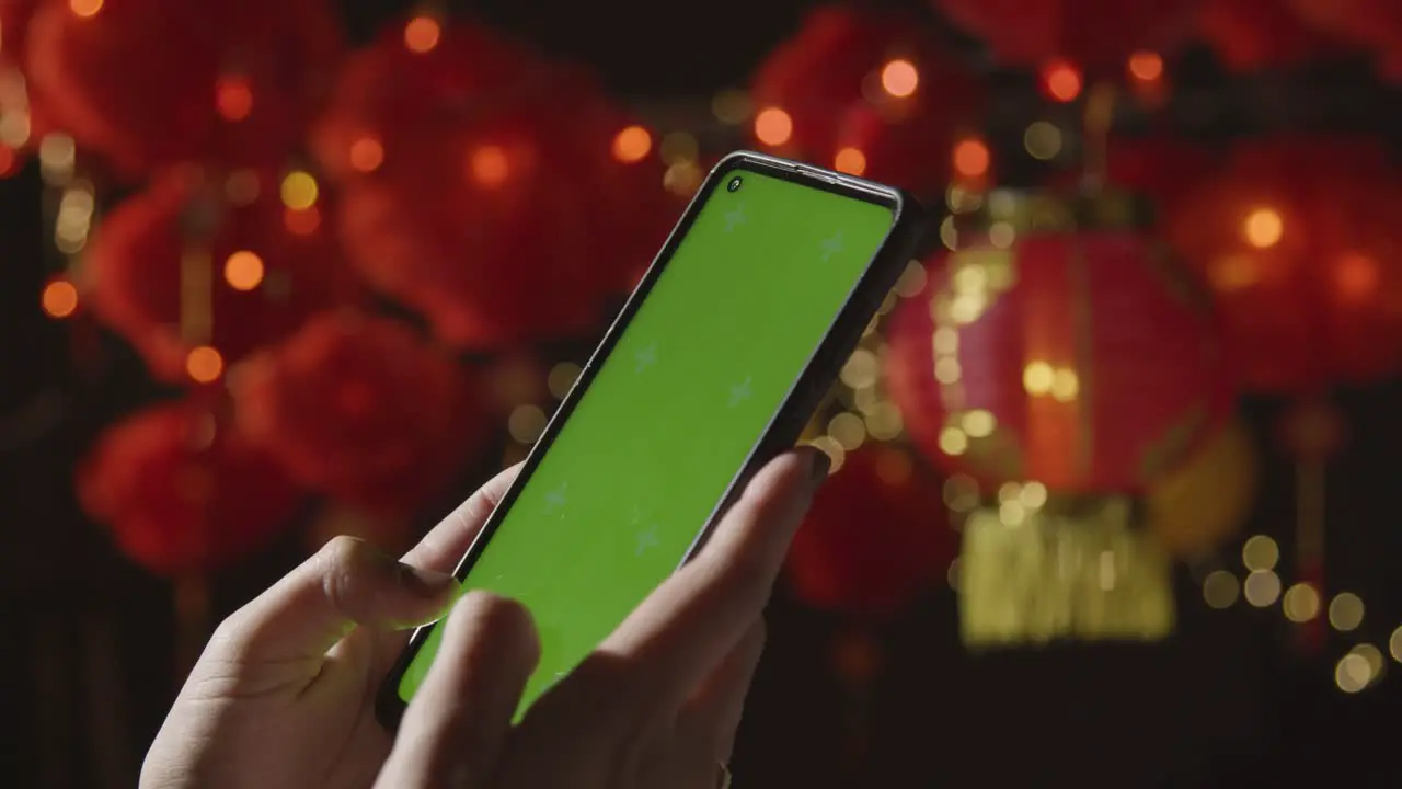 Woman Using Green Screen Mobile Phone With Chinese Lanterns Hung In Background 1