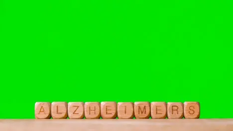 Medical Concept With Wooden Letter Cubes Or Dice Spelling Alzheimer's Against Green Screen