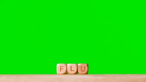 Medical Concept With Wooden Letter Cubes Or Dice Spelling Flu Against Green Screen Background