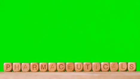 Medical Concept With Wooden Letter Cubes Or Dice Spelling Pharmaceuticals Against Green Screen Background