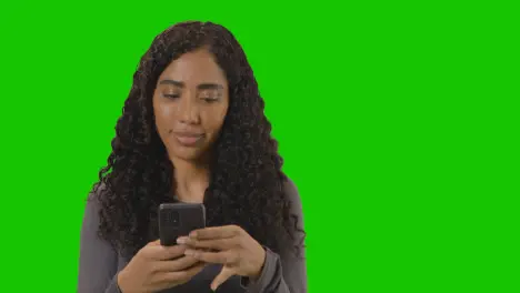 Portrait Of Woman Text Messaging On Mobile Phone Against Green Screen