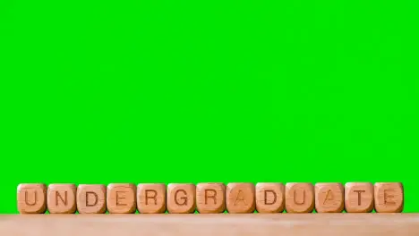 Education Concept With Wooden Letter Cubes Or Dice Spelling Undergraduate Against Green Screen