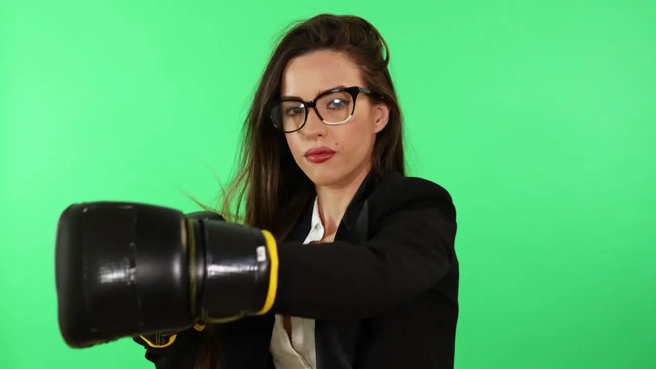 Sexy brunette young woman with glasses white shirt and black business suit wearing boxing gloves and punching stress