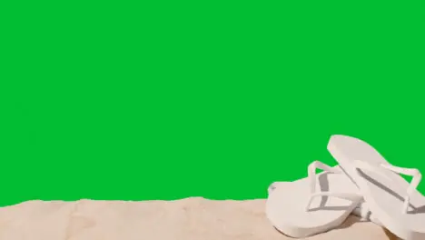 Summer Holiday Concept Of Flip Flops Beach Towel On Sand Against Green Screen