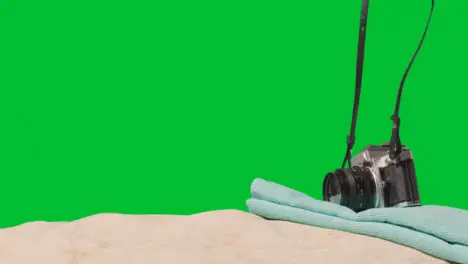 Summer Holiday Concept Of Person Putting Down Camera Beach Towel On Sand Against Green Screen