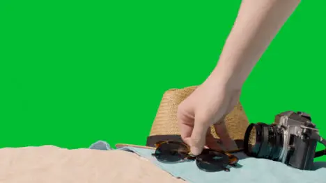 Summer Holiday Concept Of Sunglasses Sun Hat Camera Beach Towel On Sand Against Green Screen 1