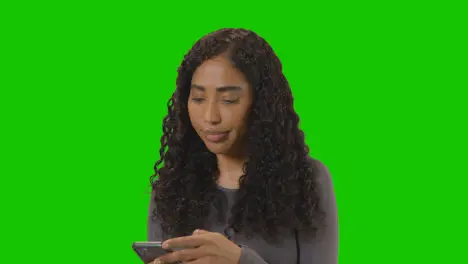 Frustrated Woman Looking At Mobile Phone Against Green Screen