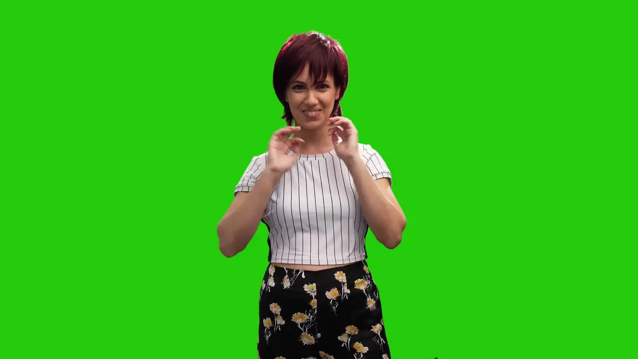 Cheerful short haired brunette female adjusting hair on green screen