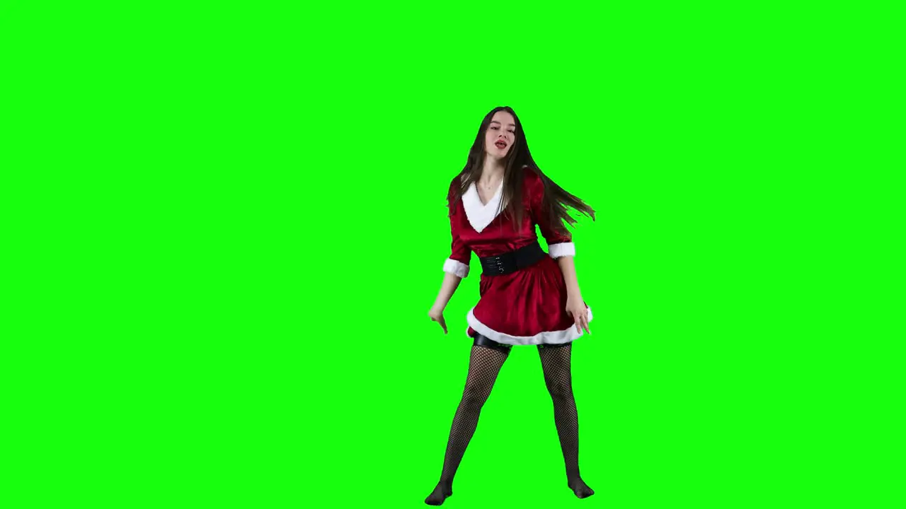 Attractive and energetic female dancer dancing in front of the green screen in Christmas costume