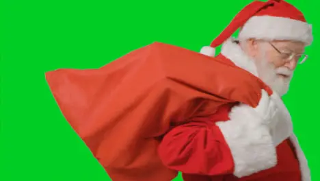 Portrait Shot of Santa Walking Into and Out of Frame Holding Sack with Green Screen