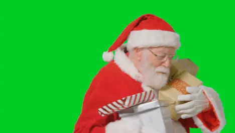 Portrait Shot of Santa Walking Into and Out of Frame Holding Presents with a Green Screen