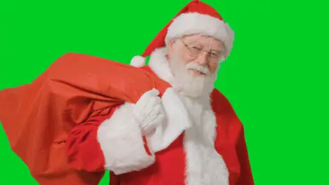 Portrait Shot of Santa Walking Into and Out of Frame Holding Sack with a Green Screen