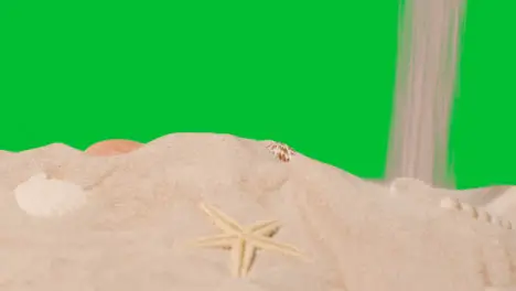 Summer Holiday Concept Pouring Sand Onto Beach With Shells Starfish Against Green Screen