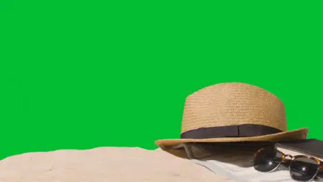 Summer Holiday Concept Of Sunglasses Book Sun Hat Beach Towel On Sand Against Green Screen